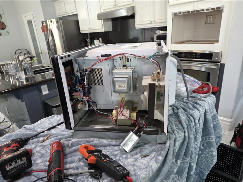 Built-in microwave repair with internal wiring and multimeter diagnostic